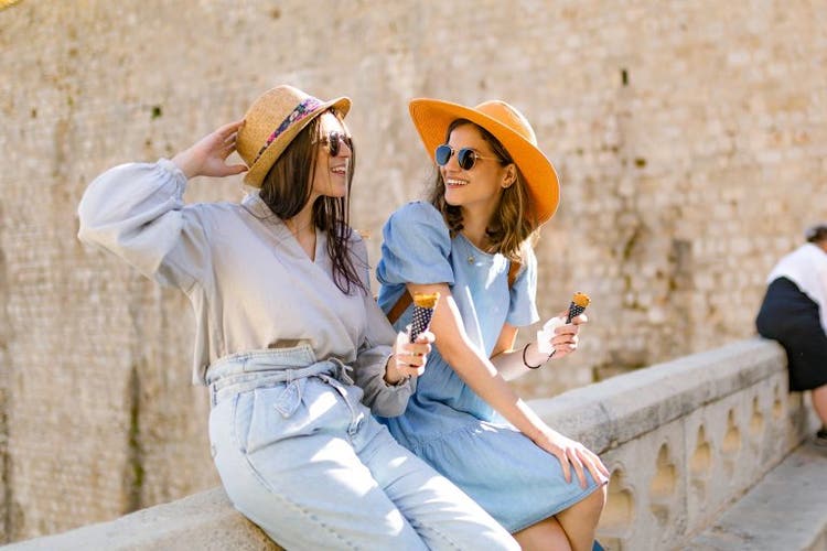 Two tourists sit on a stone wall in Dubrovnik Old Town, Croatia
