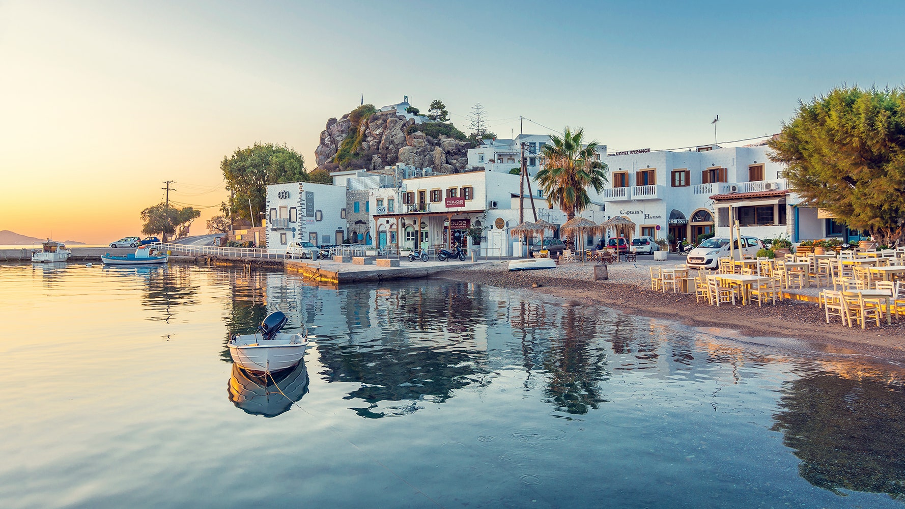 Charming coastal village with white and blue-accented buildings, a peaceful harbor, and sunset lighting, offering a relaxing Arabic cruise destination experience.
