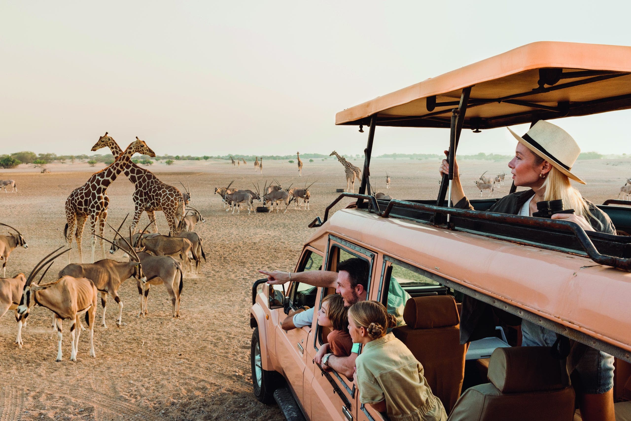 Safari vehicle with tourists watching giraffes and antelopes during a wildlife tour on a Middle East cruise excursion