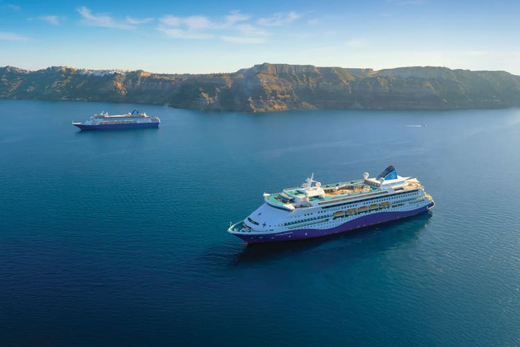 Celestyal Discovery cruise ship anchored off Santorini's caldera cliffs with Celestyal Journey ship anchored in the distance..