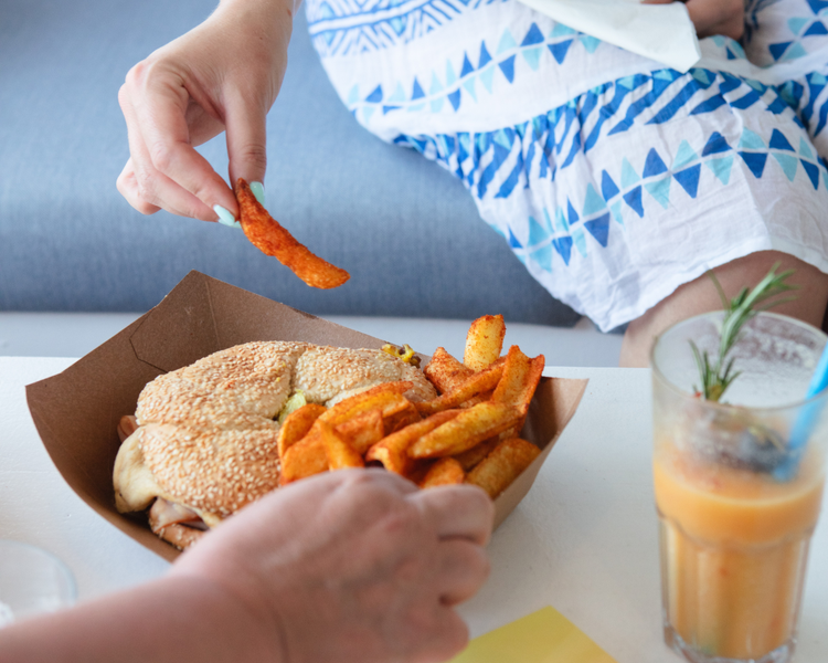 Two people take chips from a tray of food