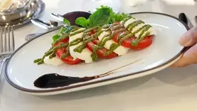 Close up shot of a Caprese salad being placed on a table