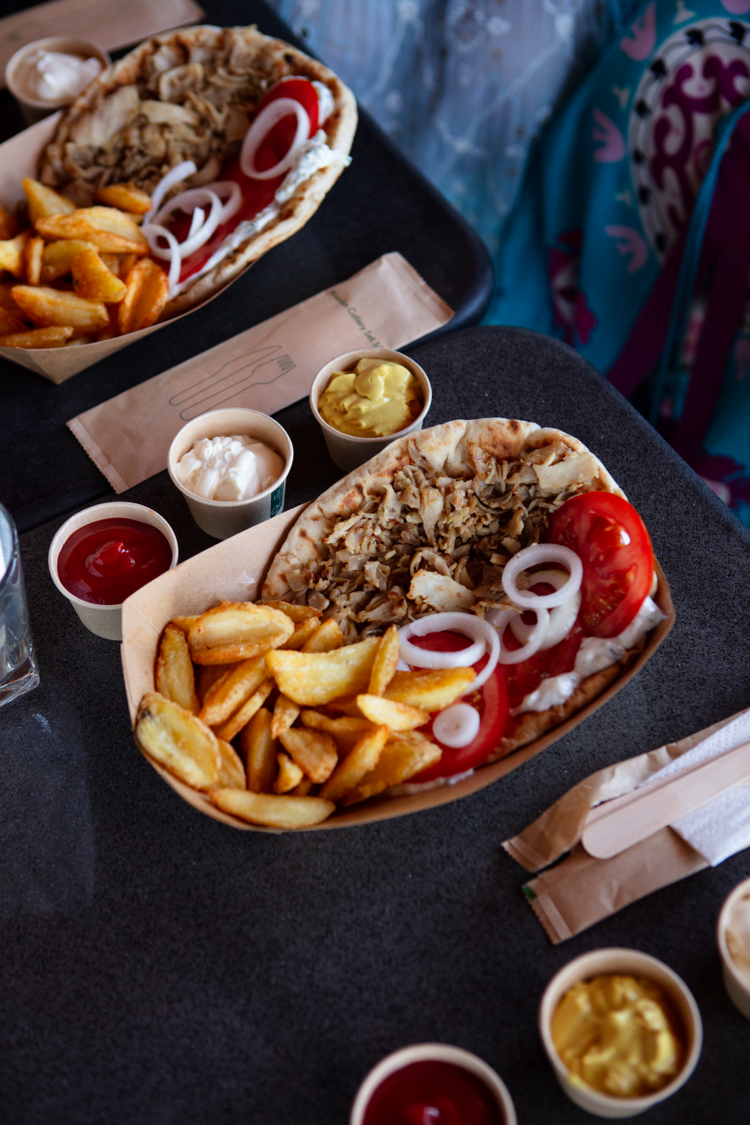 Overhead shot of two trays of Greek gyros and accompanying condiments