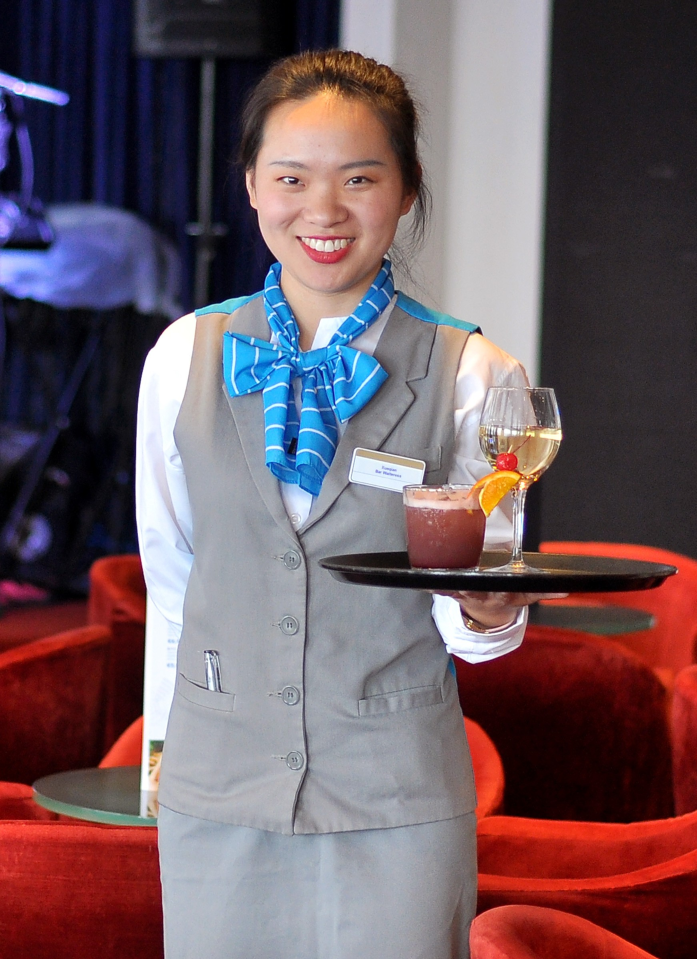 A member of Celestyal Journey crew holds a tray with two drinks on it