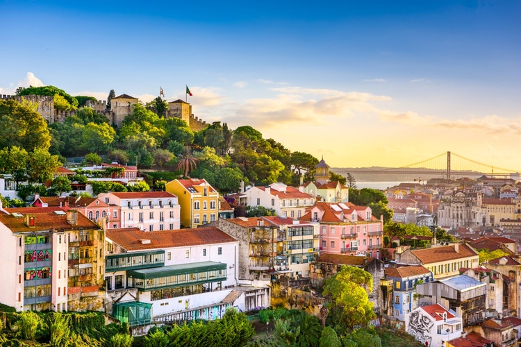 A view of houses on a hillside in Lisbon with a fortification or castle at the top - in Lisbon Portugal