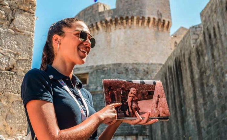 A tour guide shows an image from Game of Thrones in front of a medieval building in Dubrovnik, Croatia