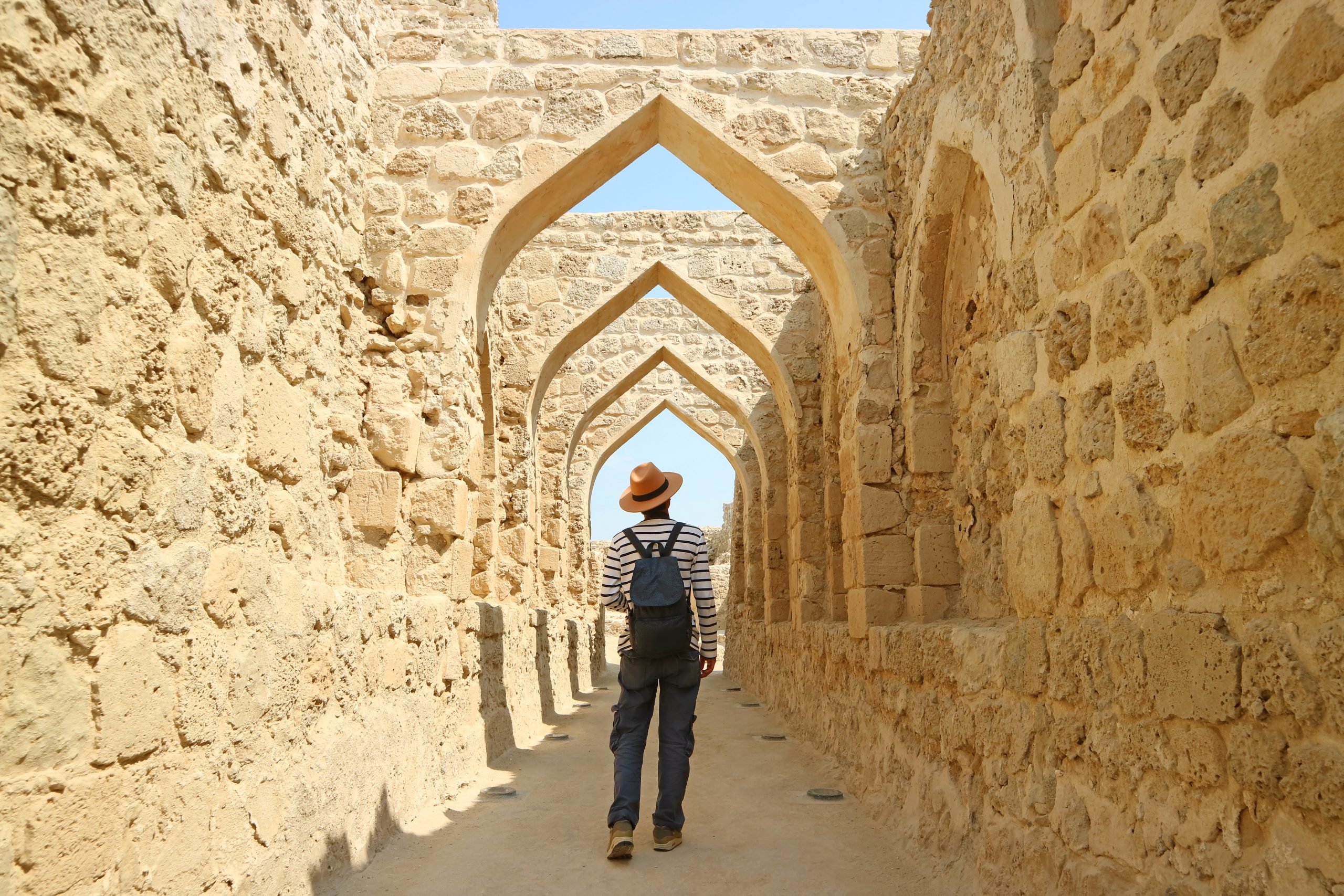 Man Walking Along the Iconic Archways in Bahrain Fort, Manama, Bahrain